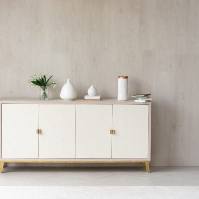 White modern dresser minimalistic furniture in empty room on grey wall background, small cupboard with decor, vases and lily of the valley flowers bouquet, cozy apartment house interior concept